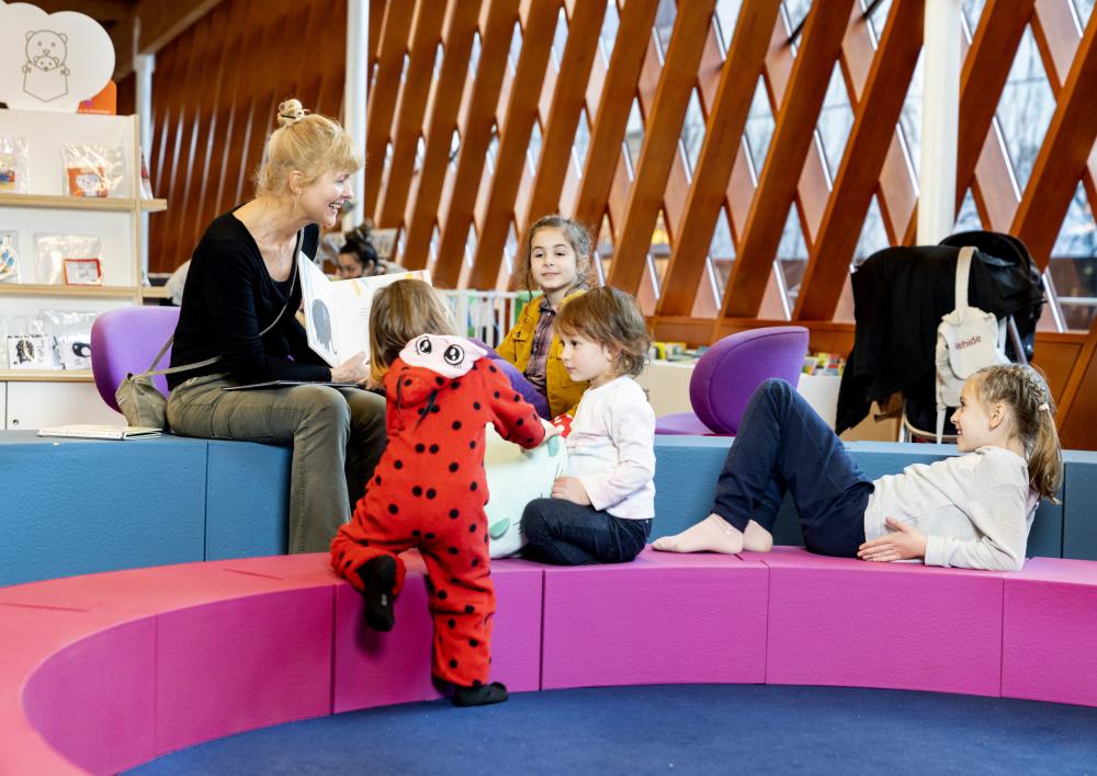 Vrouw leest kinderen voor in de Bibliotheek